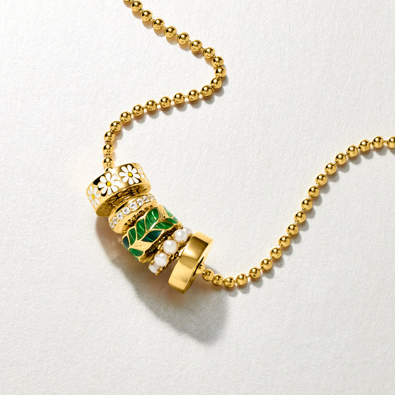 Gold bead charm with green enamel leaf detail and white stone accents