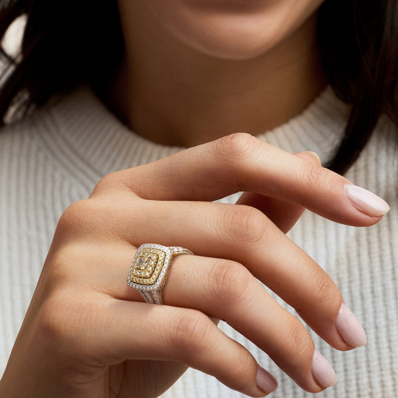 Two-tone diamond cluster ring on hand with square yellow center and white halo