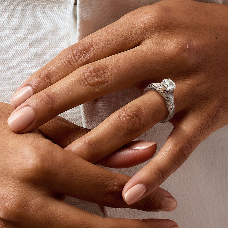 Vintage 14kt white gold diamond ring on hand with round center stone and textured setting
