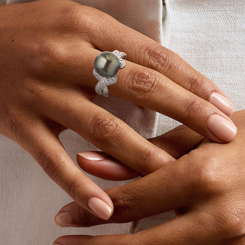 Cultured pearl ring on hand, dark iridescent round pearl with small diamond accents