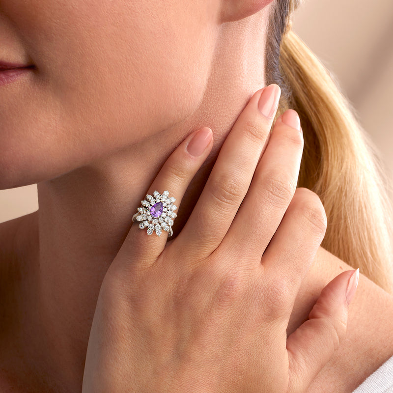 Amethyst and diamond cluster ring on hand with pear-shaped purple center, white gold