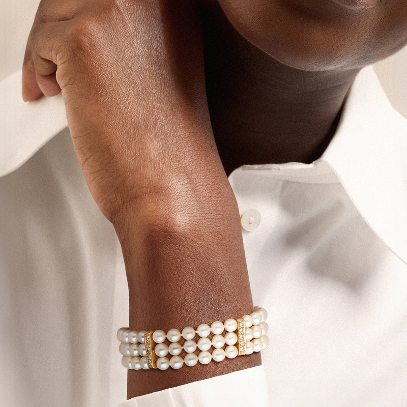 Cultured pearl three-row bracelet on wrist with gold clasp and diamond trim