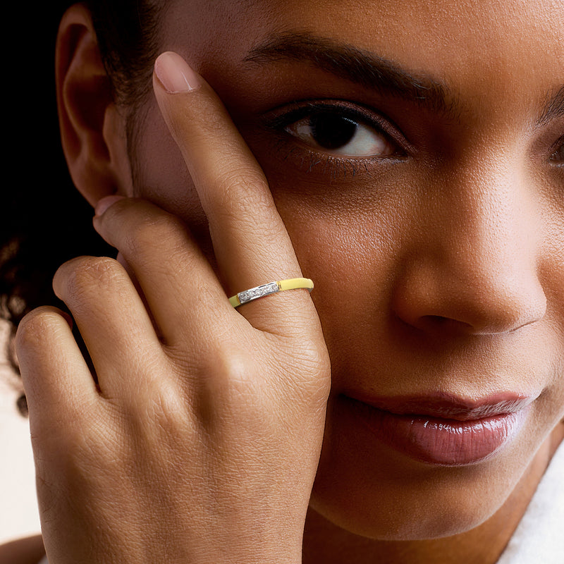 Gold ring with yellow enamel and small diamonds on finger