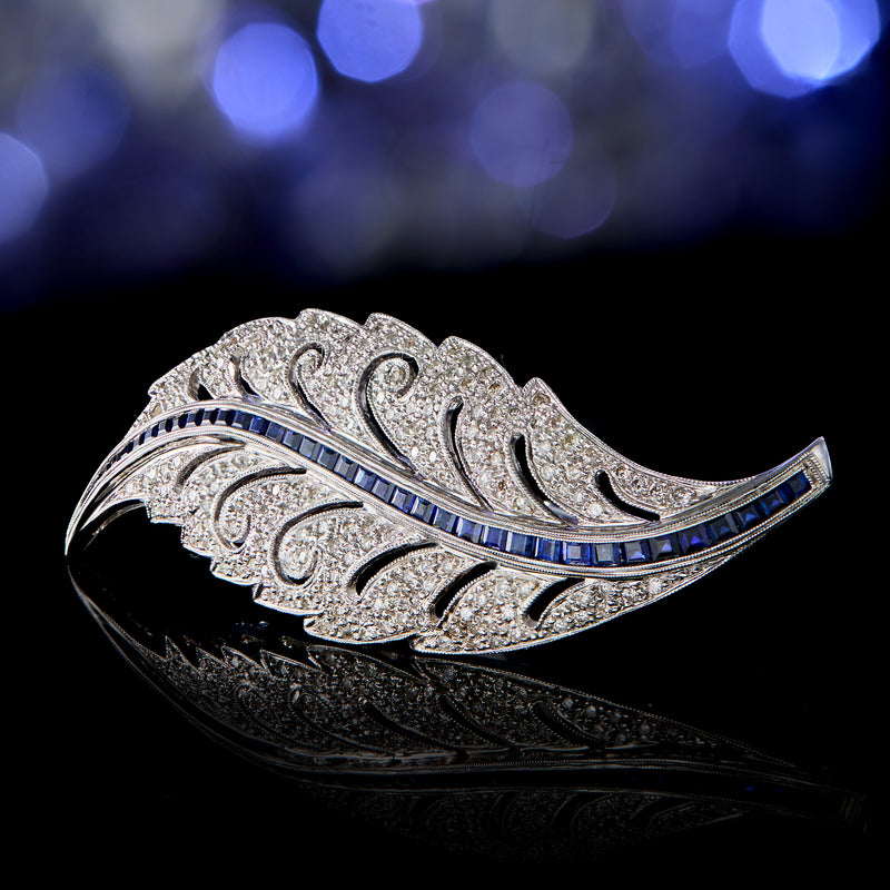 Leaf pin in white gold with diamond scrollwork and blue sapphire center line