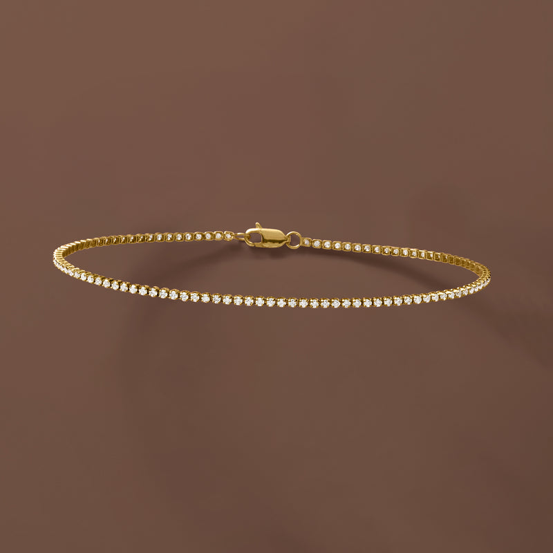 Diamond tennis bracelet on yellow gold with box clasp, continuous round stone row.