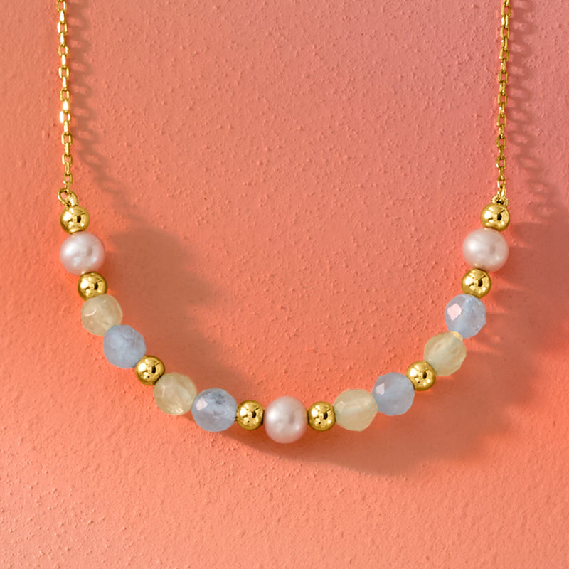 Close-up gold beaded necklace with pearls and light blue gemstone and gold beads