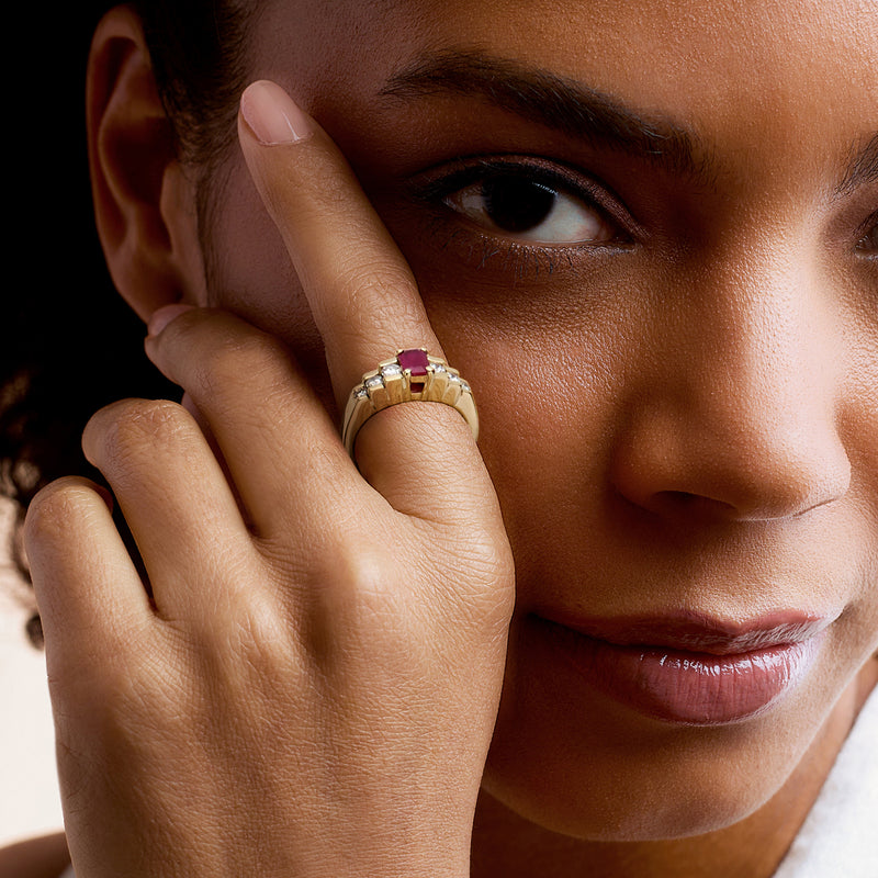 Yellow gold ruby and diamond ring on finger with rectangular pink center stone