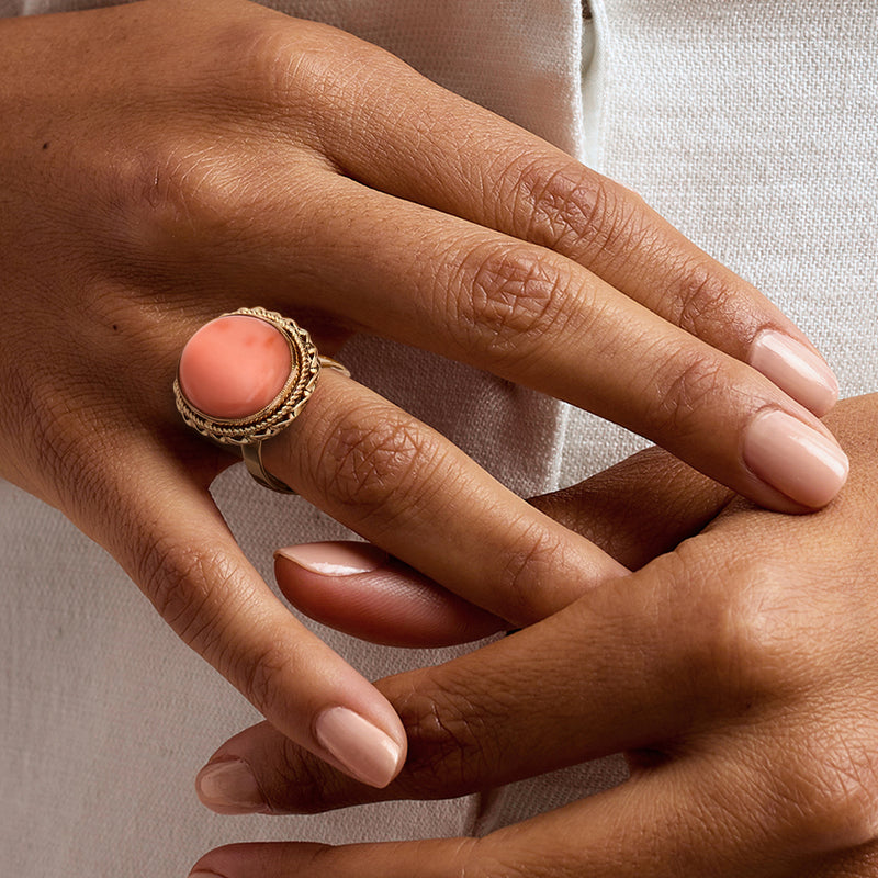 Coral oval vintage ring in 14kt yellow gold worn on hand with braided bezel