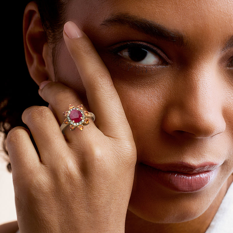 Yellow gold ring with pink ruby center and colorful stones, worn on finger