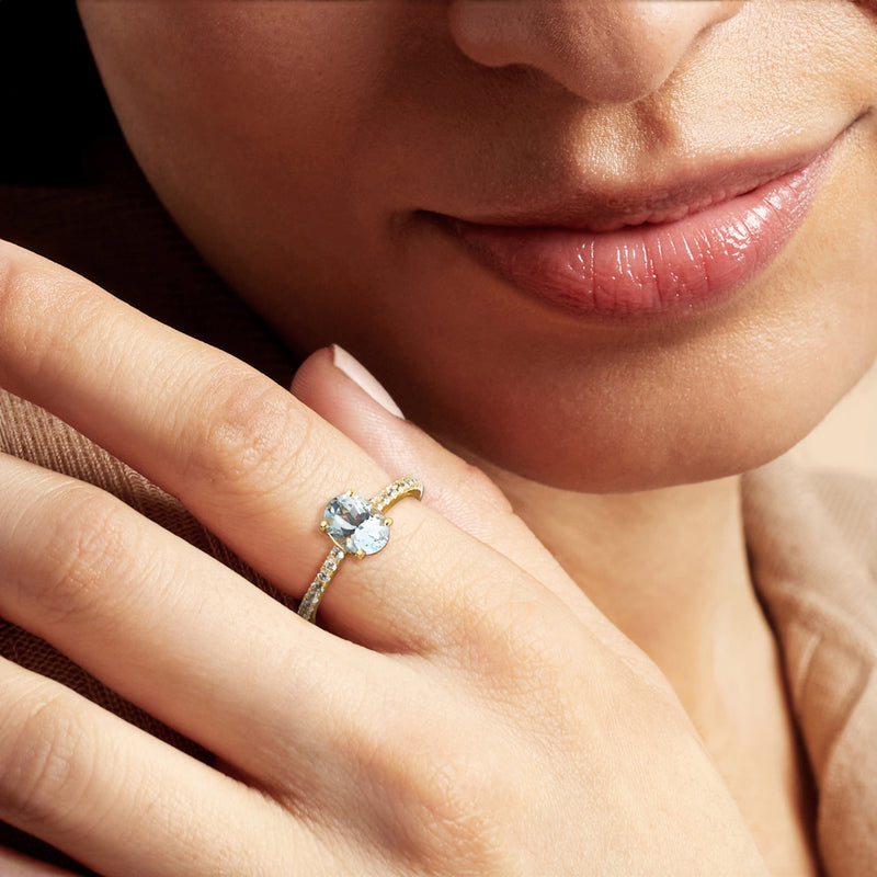 Aquamarine oval and small diamond band ring worn on finger, close-up