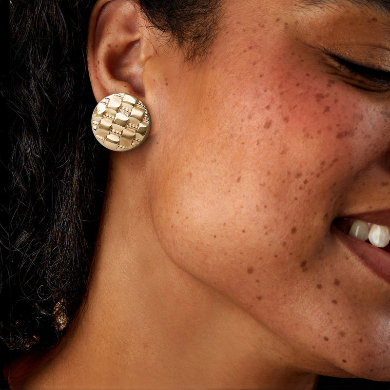 Yellow gold basketweave button earrings worn on ear, round domed textured design.