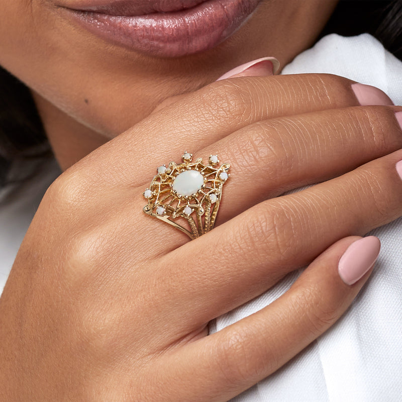 Yellow gold opal ring on hand, oval opal center with small sparkle accents, close-up
