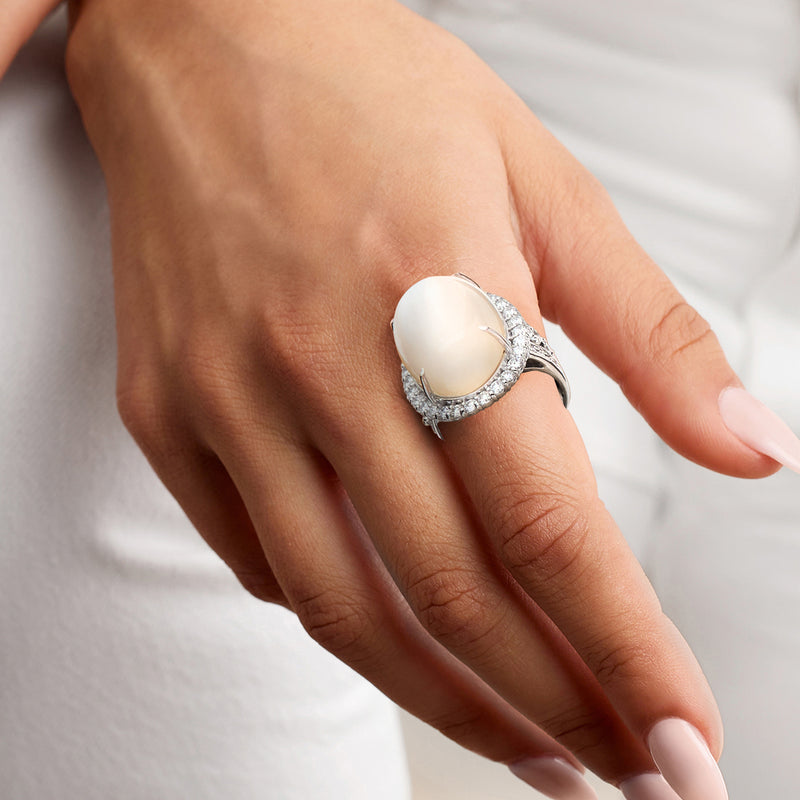 Platinum moonstone and diamond ring on model's hand with oval cabochon centerpiece