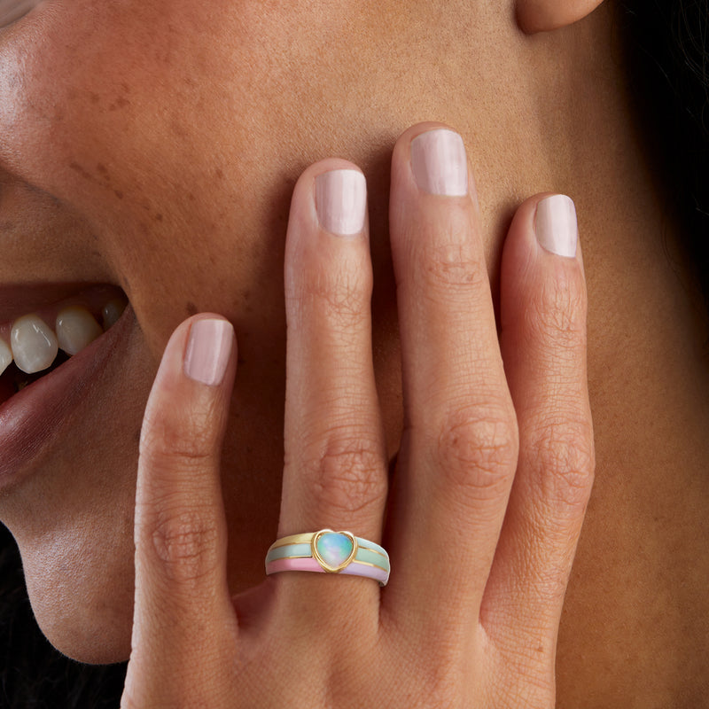 Gold ring on hand with pastel enamel heart center and small opal oval