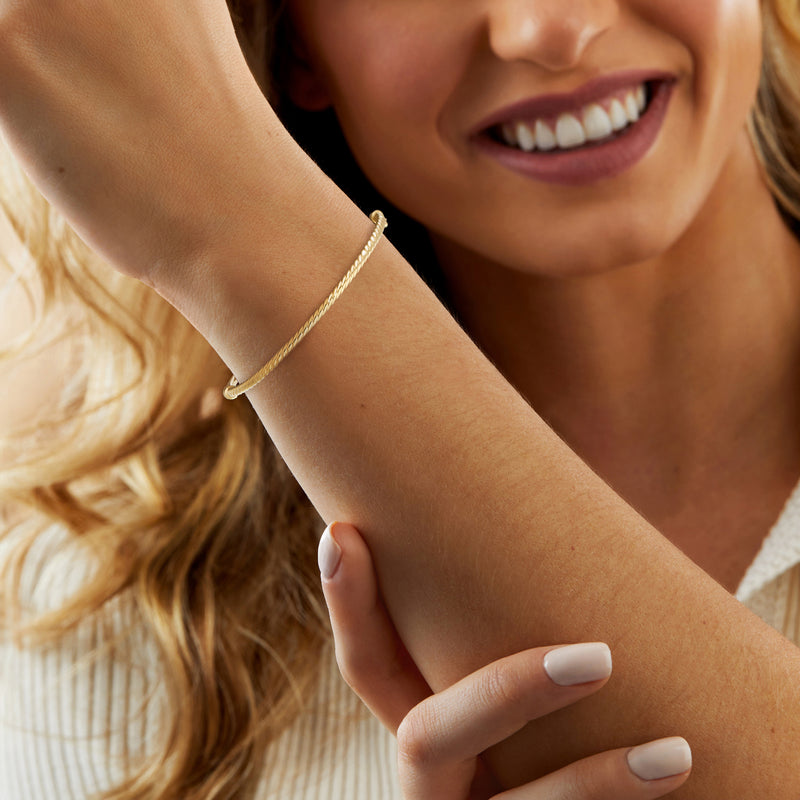 10kt yellow gold ribbed bangle bracelet on wrist, close-up