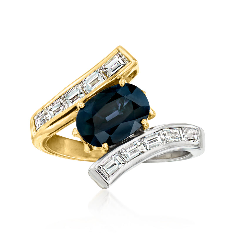 Two-tone gold bypass ring with dark blue oval center stone and baguette diamond accents