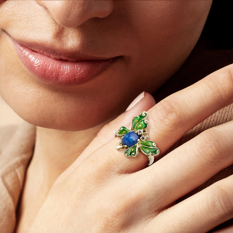 Butterfly ring on hand: blue oval stone, green enamel leaves, diamond sparkle