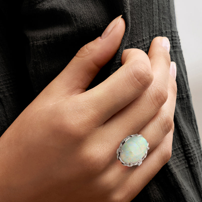 Opal cabochon ring on hand, oval stone in silver-toned setting, size 7