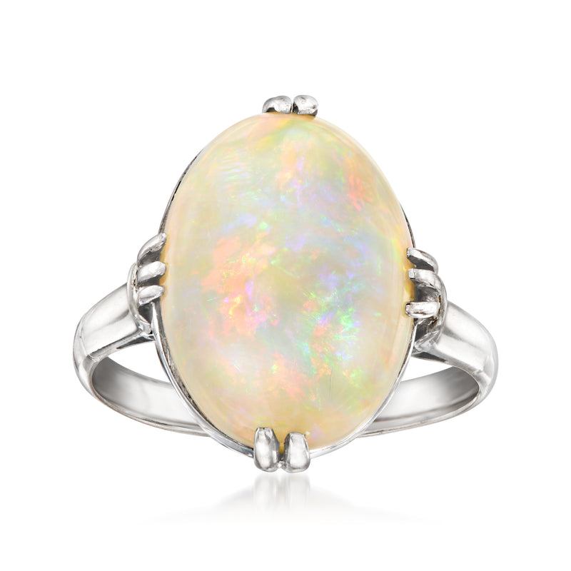 Platinum ring with oval opal centerpiece and raised prongs, iridescent pale color.