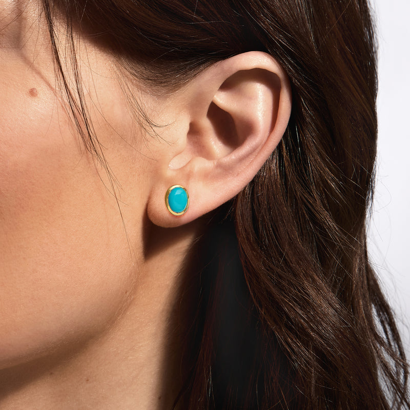 Gold-tone bezel turquoise stud earrings on ear, round turquoise gemstone