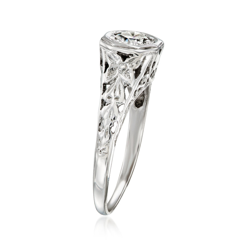 White gold ring with round diamond center, raised prongs and filigree side detail