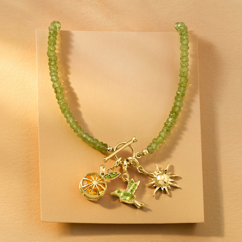 Green beaded necklace with gold-tone charms, including orange citrine slice and green stones