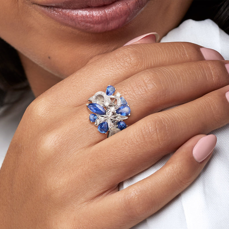 Blue sapphire cocktail ring with diamond accents in white gold, worn on hand