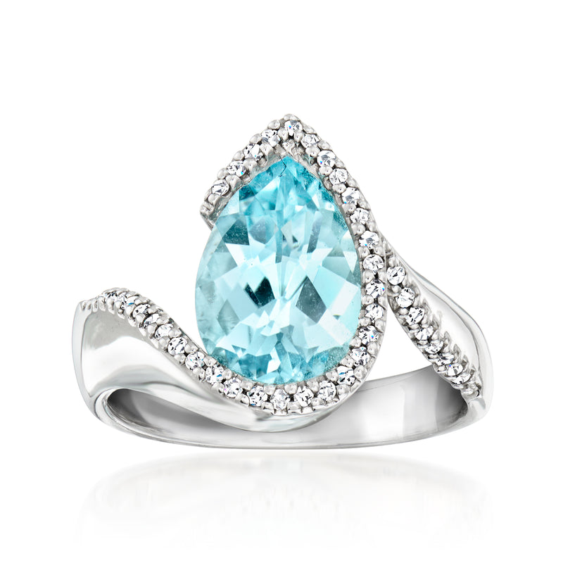 White gold ring with light blue topaz center and diamond halo, swirl split band