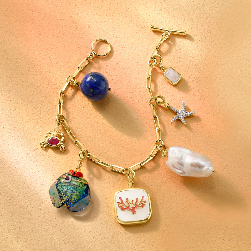 Gold charm necklace featuring a round blue lapis bead charm among mixed dangling charms.