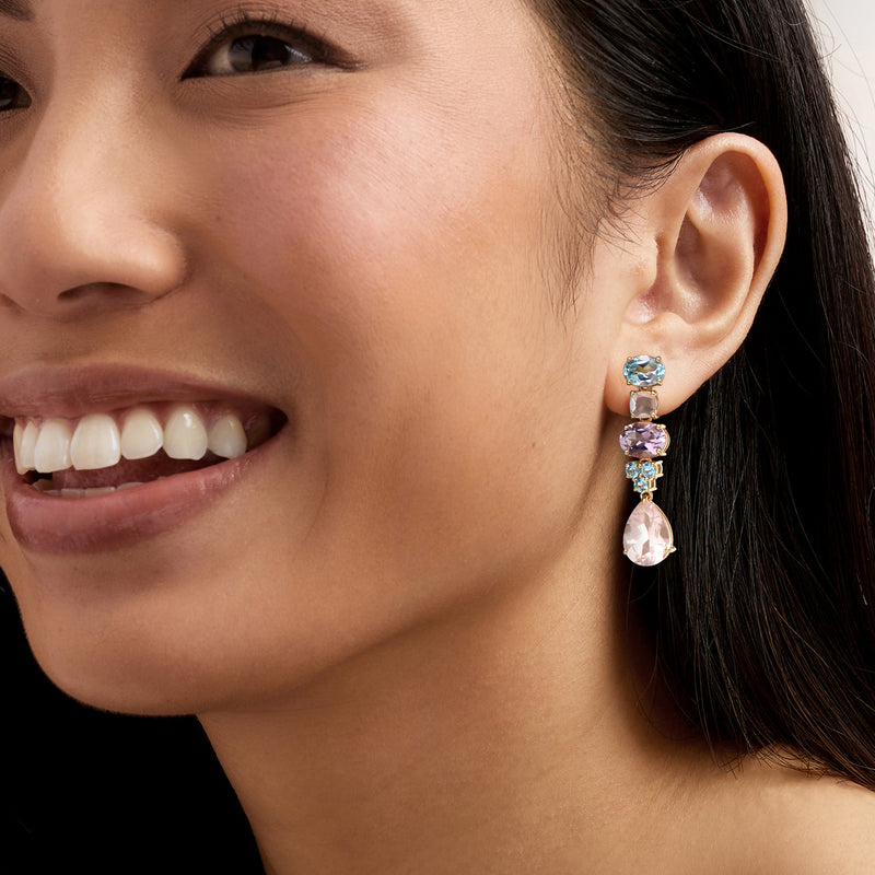 Gold-tone multi-gem drop earring set on ear with blue, purple, and rose teardrop stones