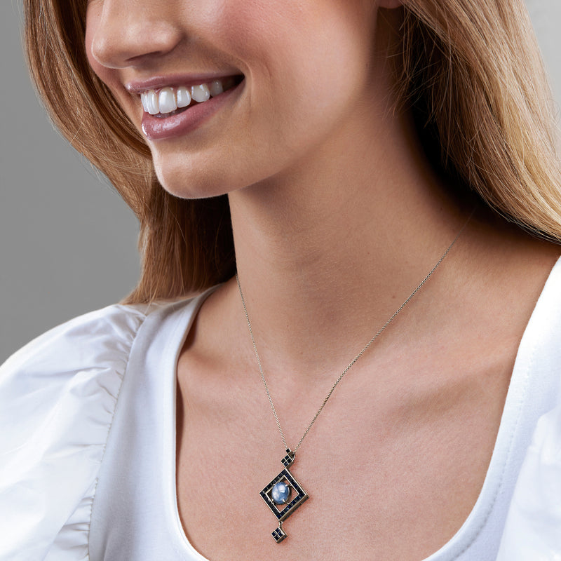 Platinum sapphire pendant necklace on model, square blue gemstones with light blue center