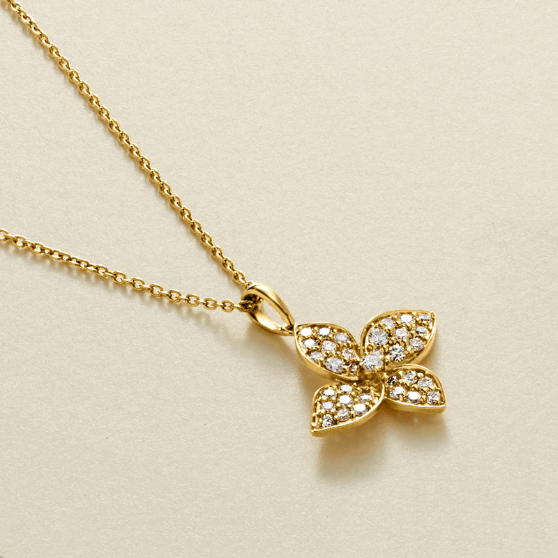 Gold flower pendant necklace close-up with sparkling round stones and link chain