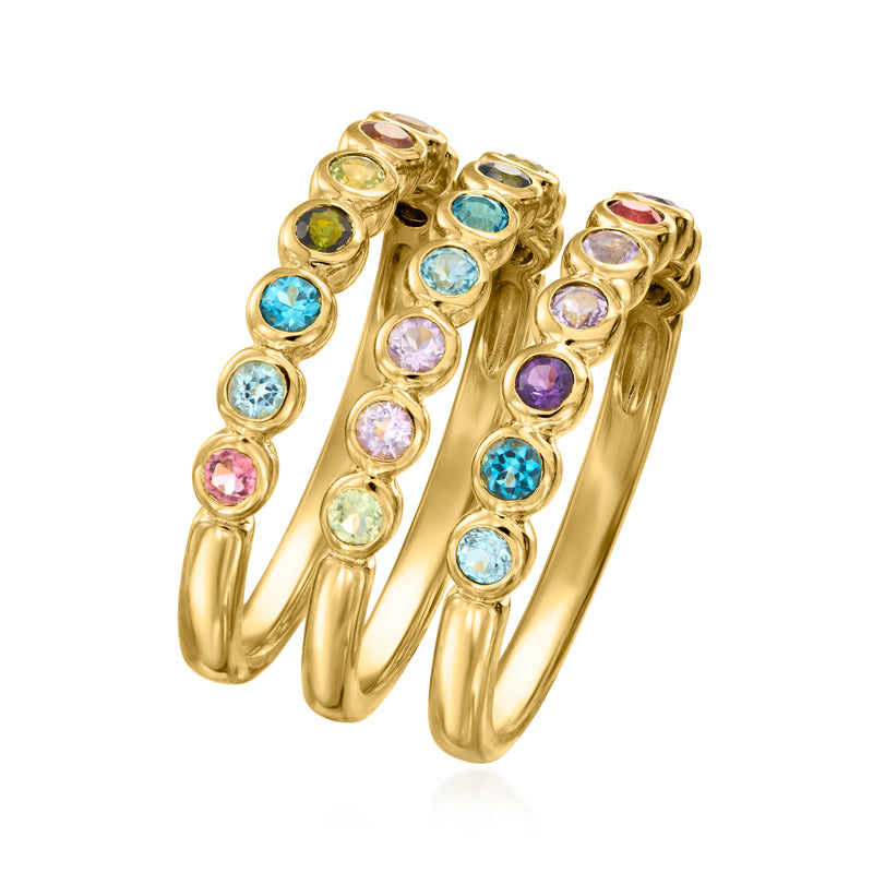 Three stackable gold-tone gemstone rings viewed at angle, round stones in mixed colors