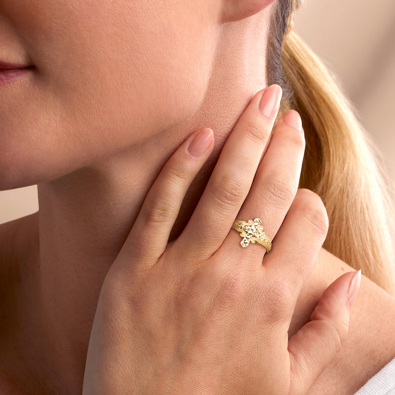 Yellow gold cross ring on finger with faceted cross top and textured band