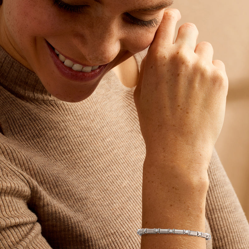 Diamond tennis bracelet in 14kt white gold worn on wrist, rectangular stone settings