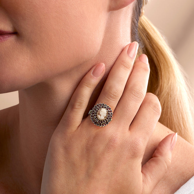 Cameo garnet halo ring on hand, oval white cameo set in yellow gold