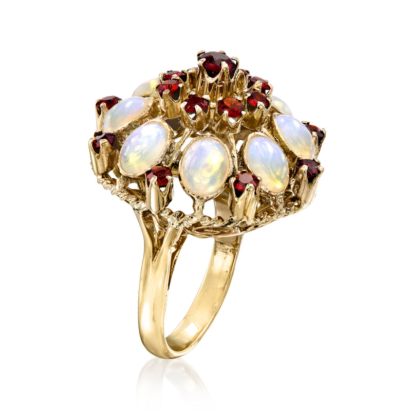 Yellow gold cluster ring with white opal center and red ruby gemstones, angled view