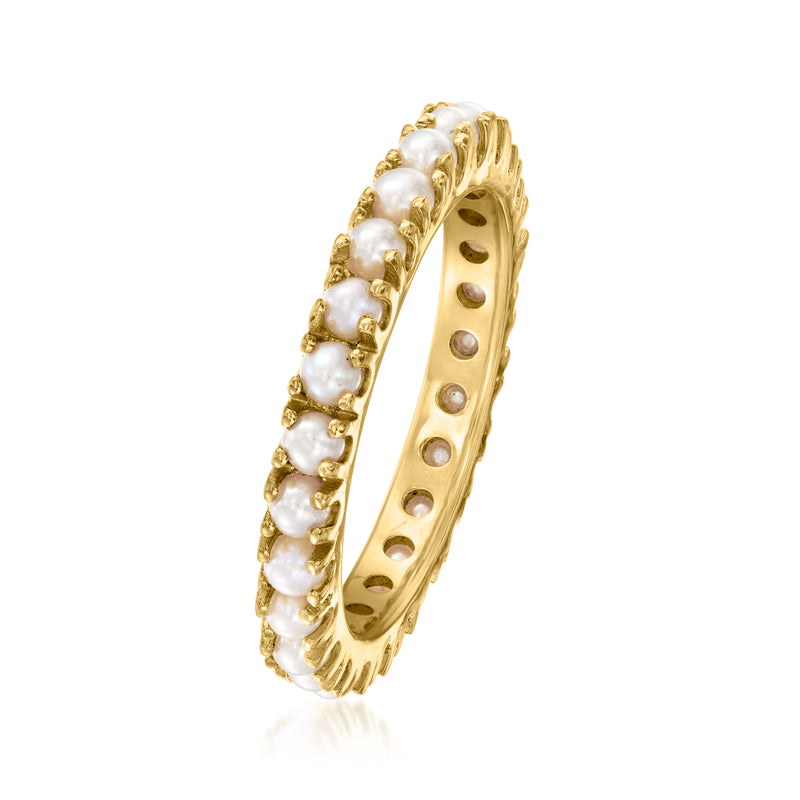 Gold eternity band ring with small round white pearls along the side, openwork center