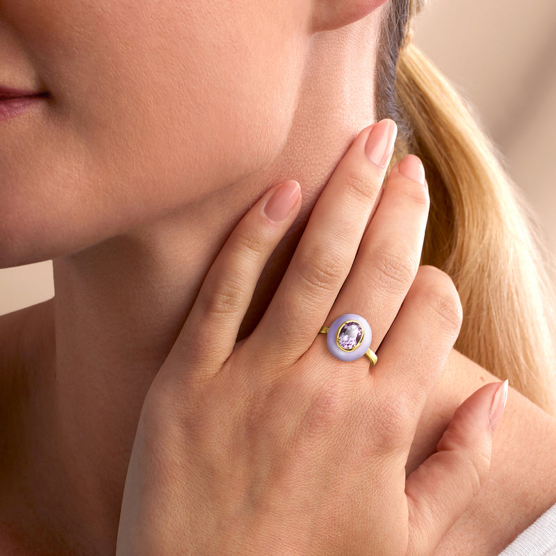 Lavender enamel and gold ring with oval purple gemstone on model's finger