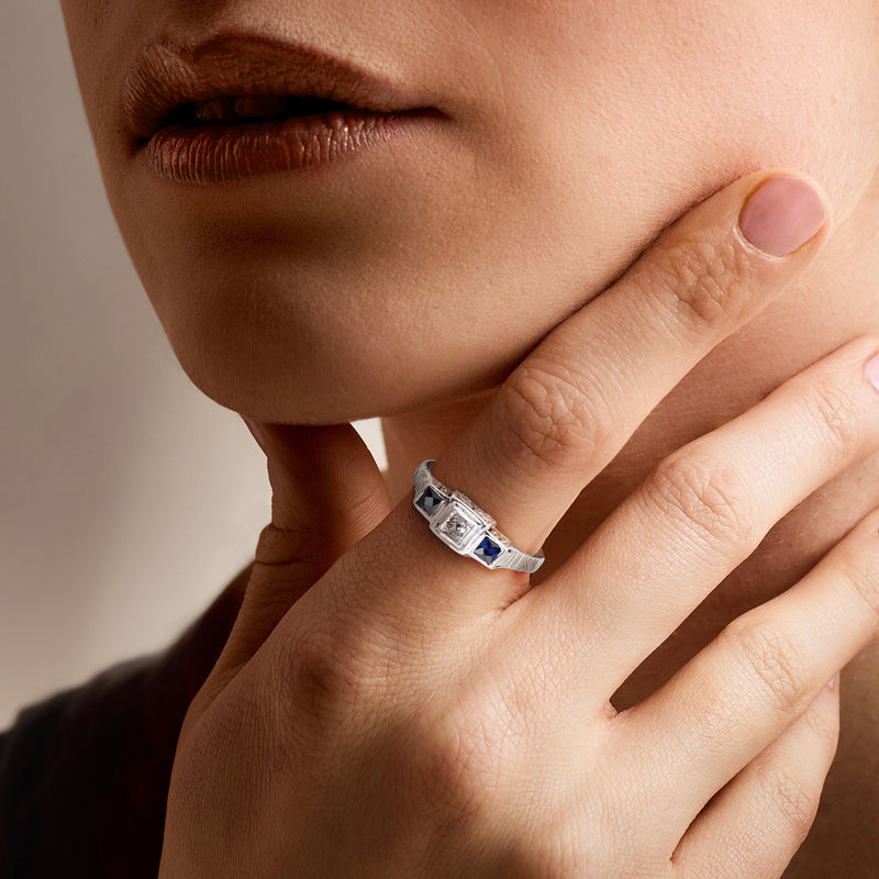 Vintage sapphire and diamond ring on hand, dark blue stone in white gold setting