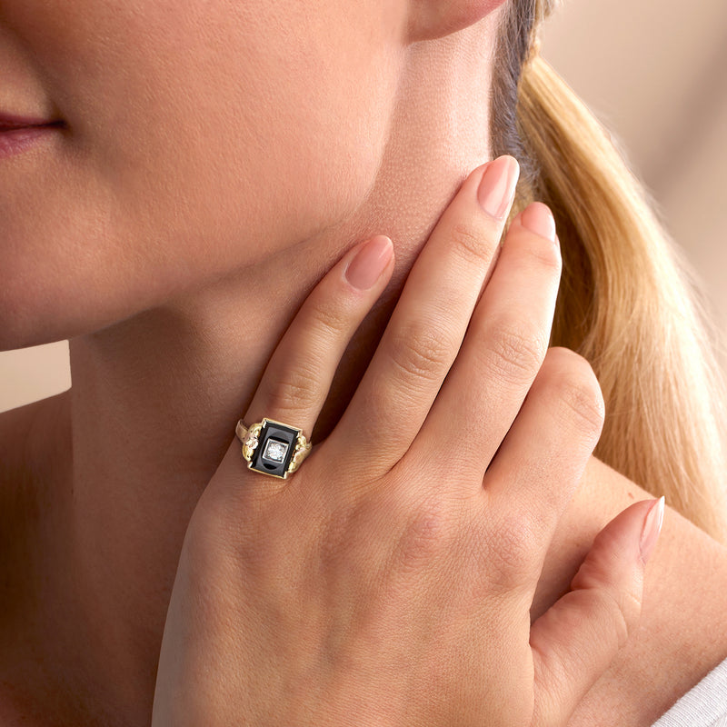 Onyx and diamond tri-colored gold ring on finger with square black center