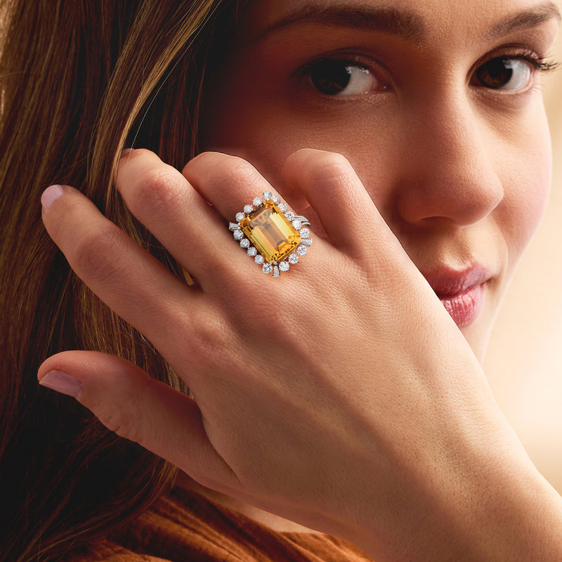 Citrine and diamond halo ring on hand, silver-toned setting with bright gemstone
