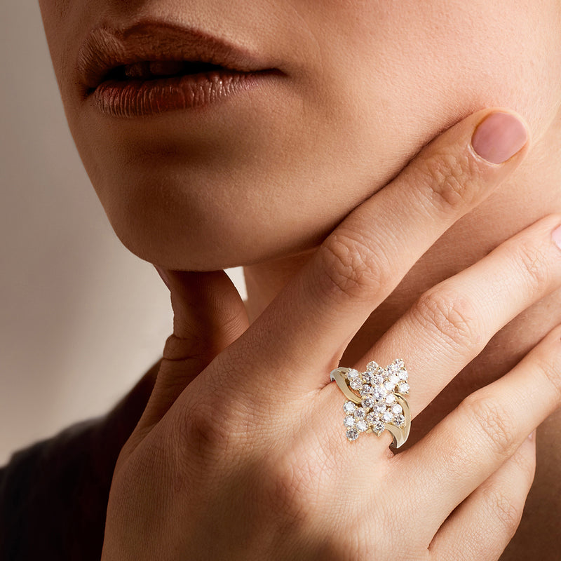 Diamond cluster ring on finger in 14kt yellow gold, round stones with raised setting