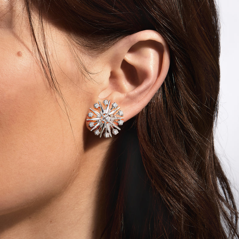Platinum starburst diamond post earrings with round stone cluster detail on ear