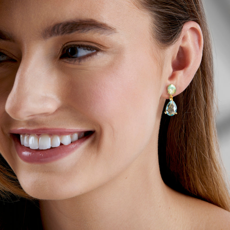 Gold drop earrings on ear: opal-like green oval top with sky-blue teardrop dangle