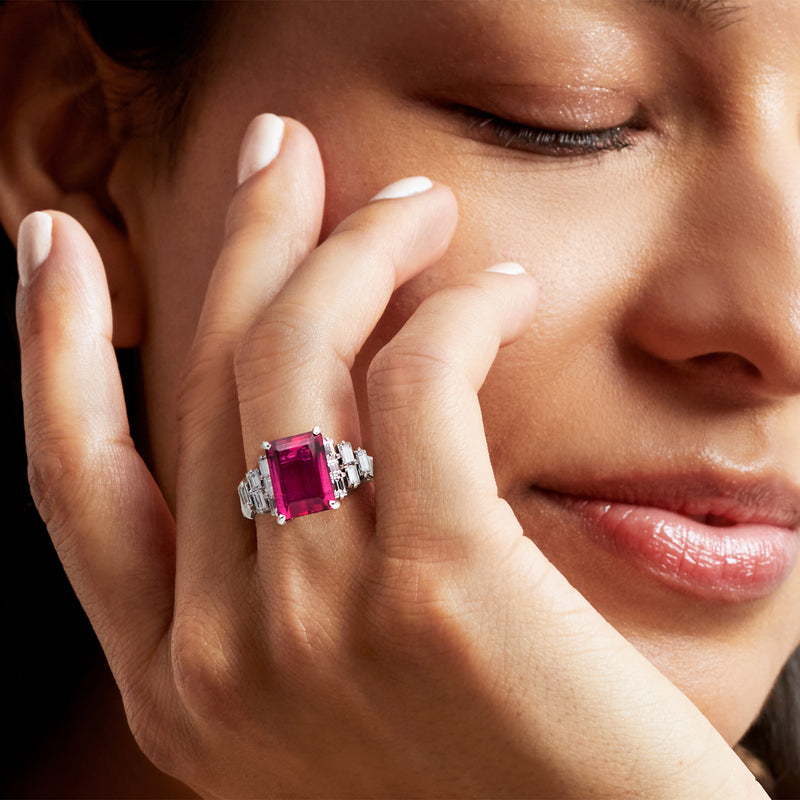 Pink gemstone and diamond ring on hand, square center stone with white-gold setting