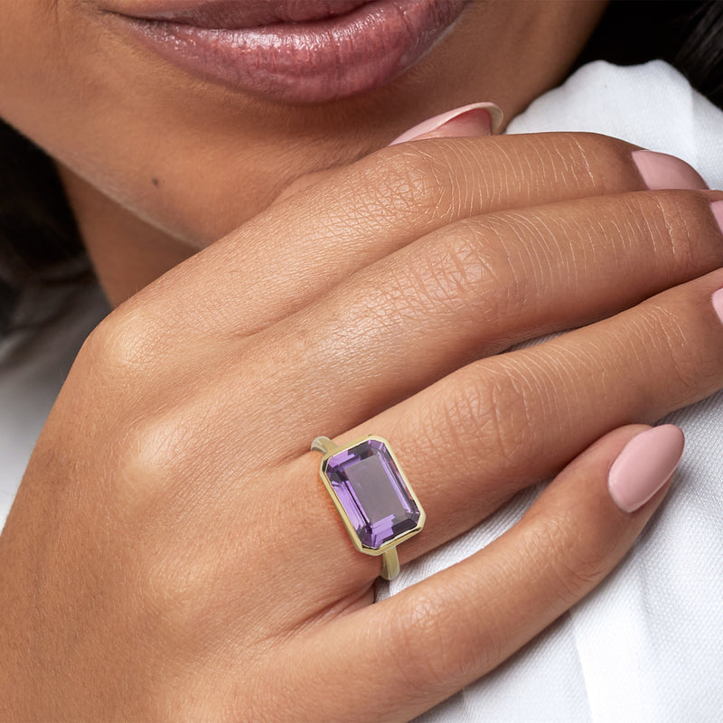 Purple amethyst square-cut gold ring worn on finger, close-up view