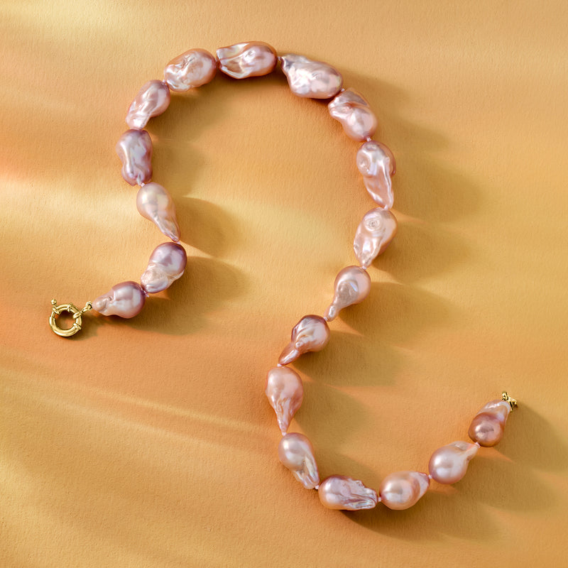Pastel baroque pearl necklace laid flat with gold over sterling clasp, curved pearls