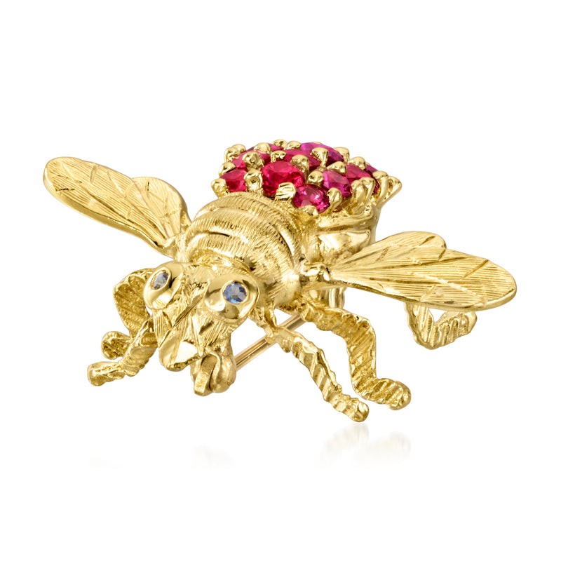 Gold bee lapel pin with pink gemstone abdomen and light stone accents.