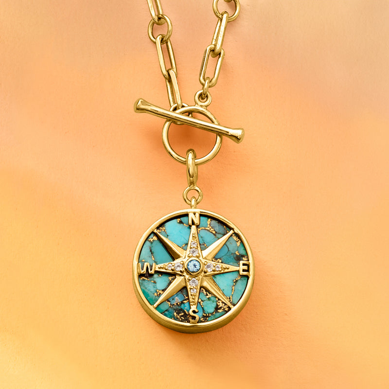 Gold compass charm pendant on chain with turquoise enamel dial and crystal center.